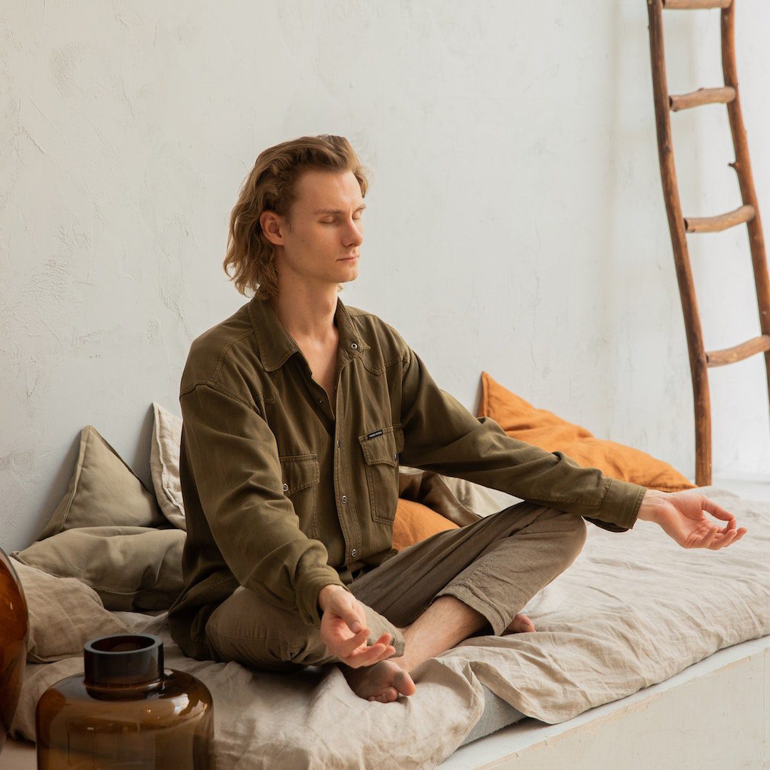 Concentrated man meditating in Lotus pose on mattress Concentrated man meditating in Lotus pose on mattress<br />